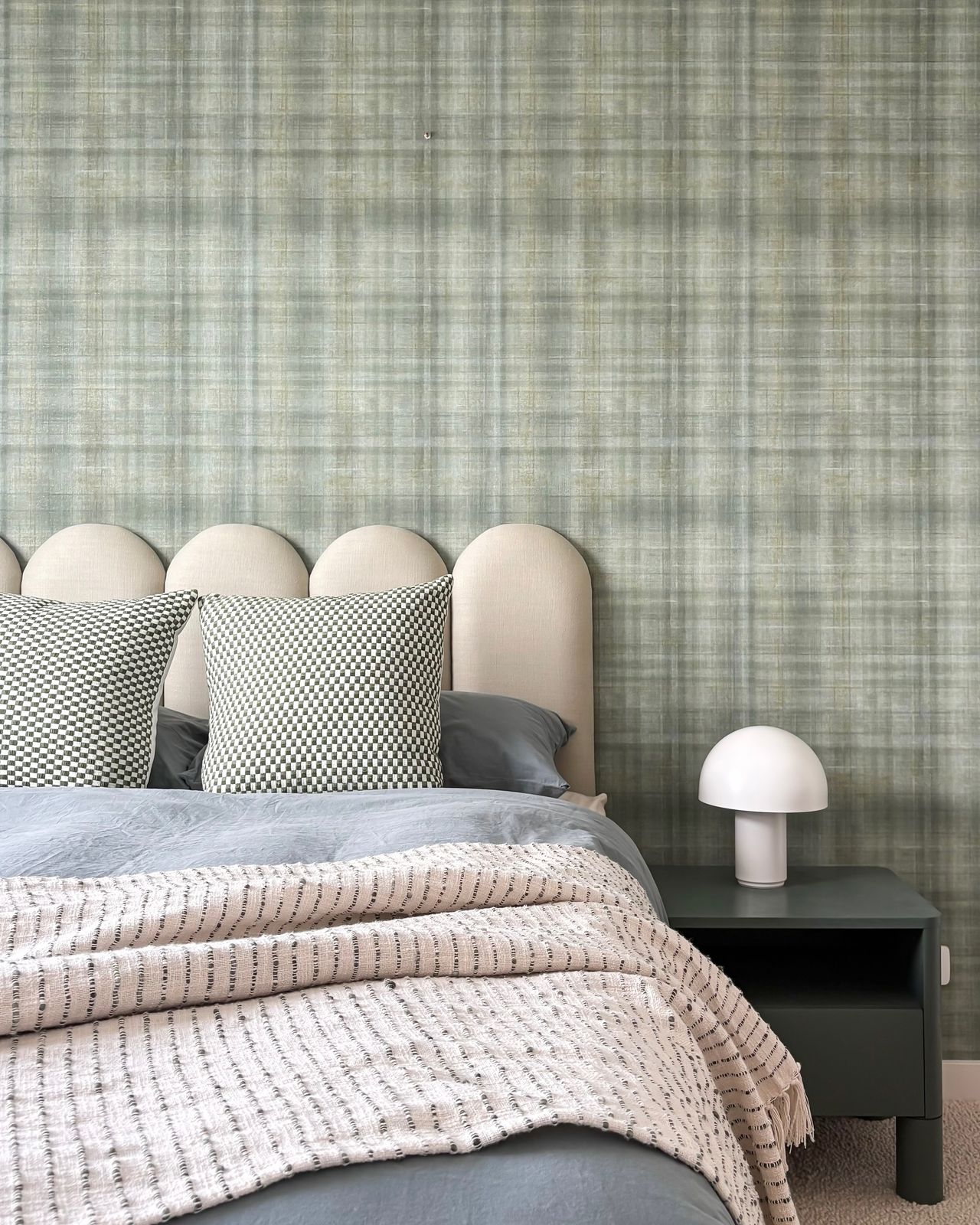 Guest bedroom with green plaid wallpaper, arched cream bedhead, and mushroom lamp