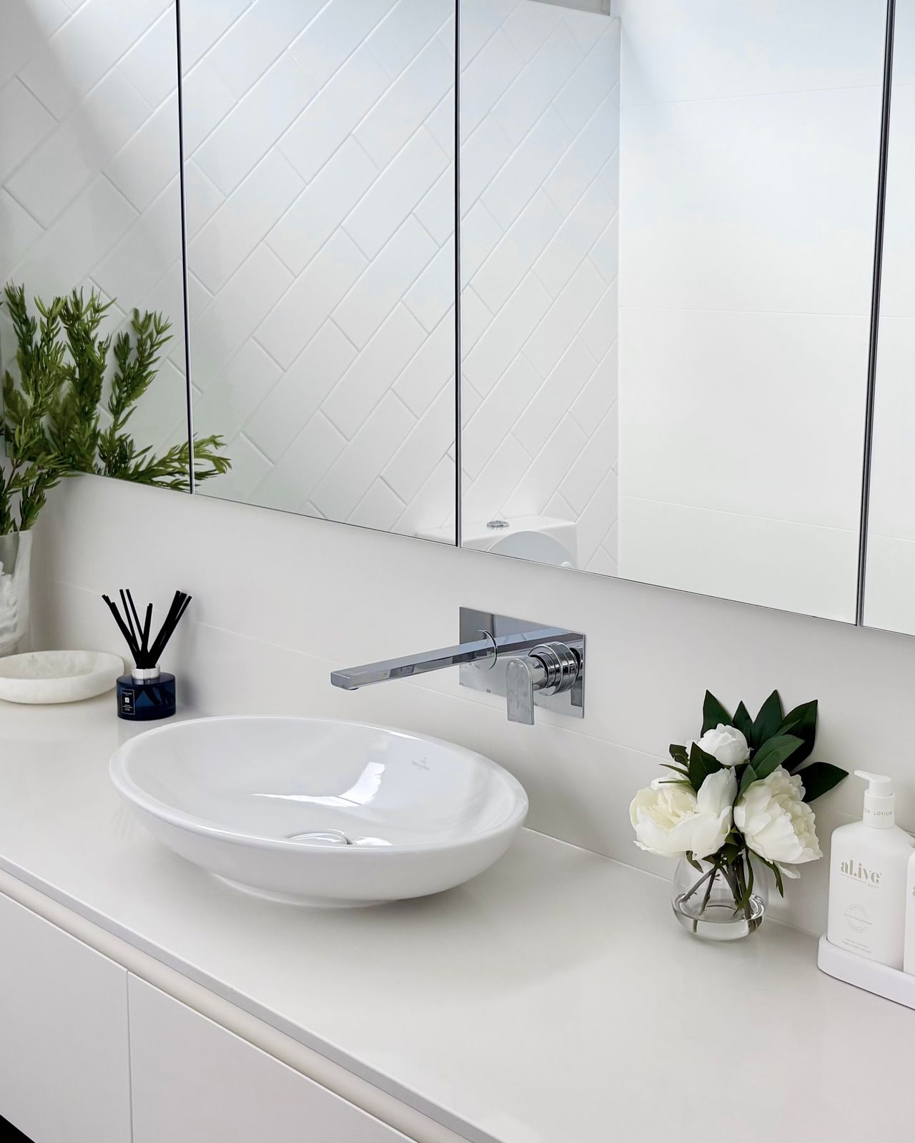 Ensuite vanity with vessel basin, white peonies, and chrome wall tap
