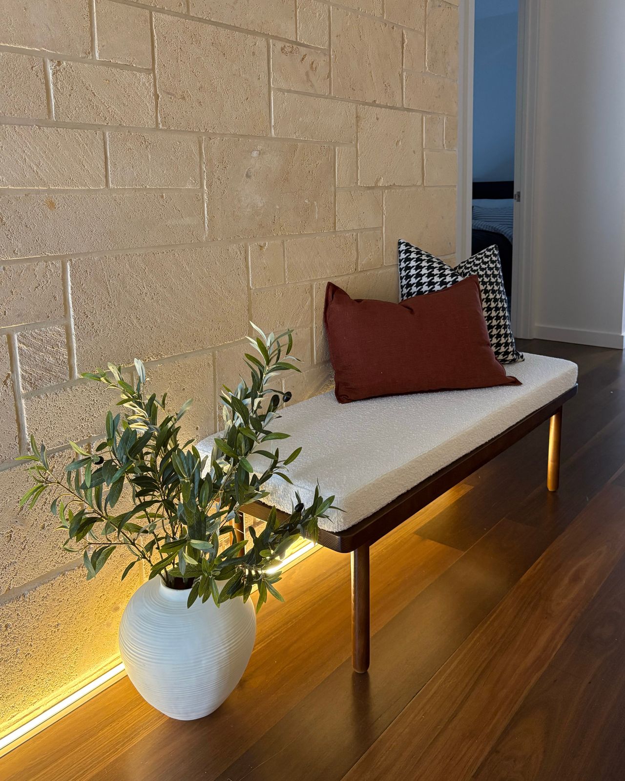 Entry bench with rust cushion and olive branch in linen vase
