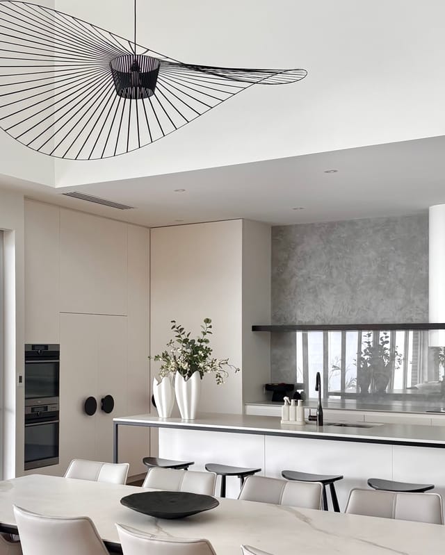 Kitchen with Vertigo pendant, plaster splashback, and sculptural white vases