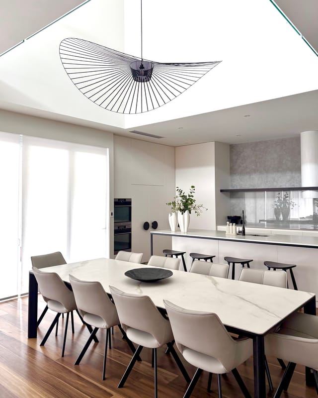 Marble dining table beneath the Vertigo pendant, with leather chairs and timber floor