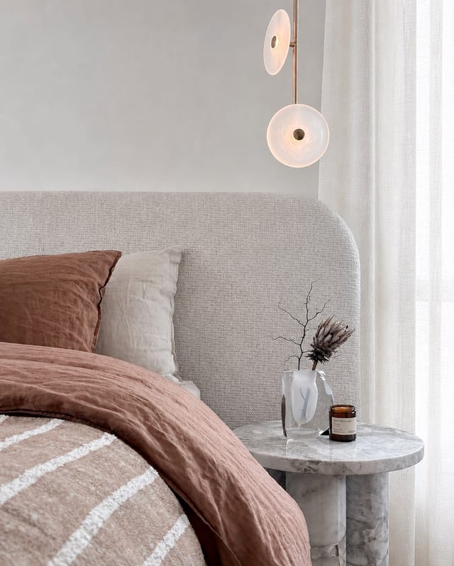 Master bedroom detail with terracotta linen, brass pendant, and marble side table