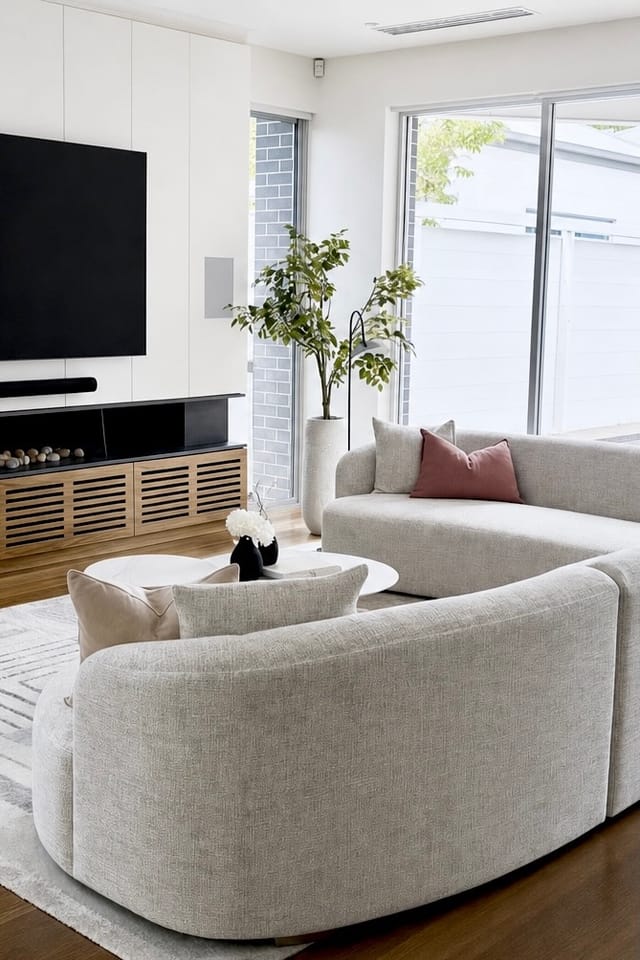 Curved cream sofa with rust velvet cushion in the open-plan living room