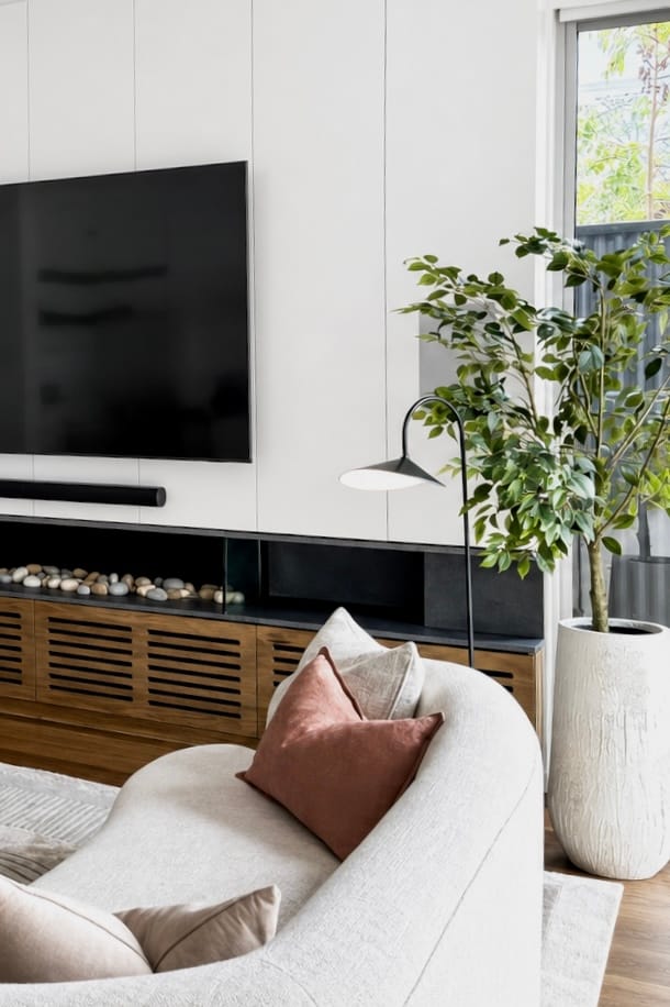 Joinery TV unit with pebble fireplace and cream curved sofa detail