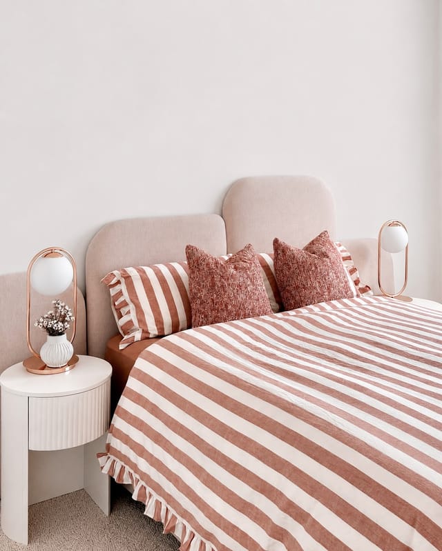 Daughter's bedroom with pink scalloped bedhead and rust striped linen